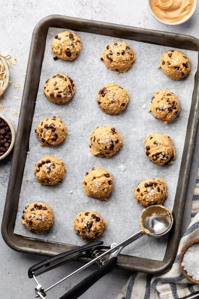 Overhead view of a sheet pan lined with parchment paper topped with cookie dough bites.