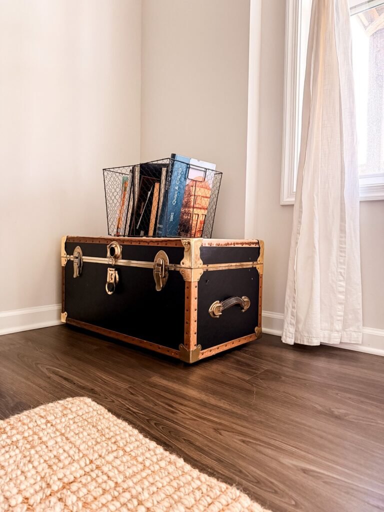 a trunk with a stack of books on top in a wire basket