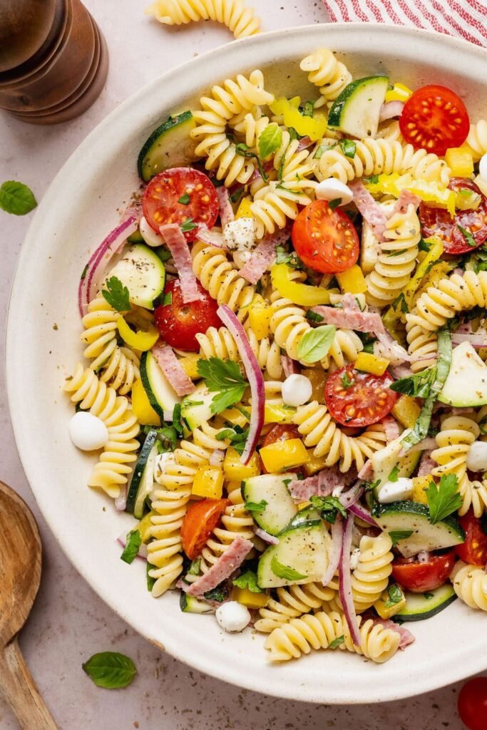 Overhead view of a colorful Zesty Italian Pasta Salad topped with fresh herbs and black pepper.