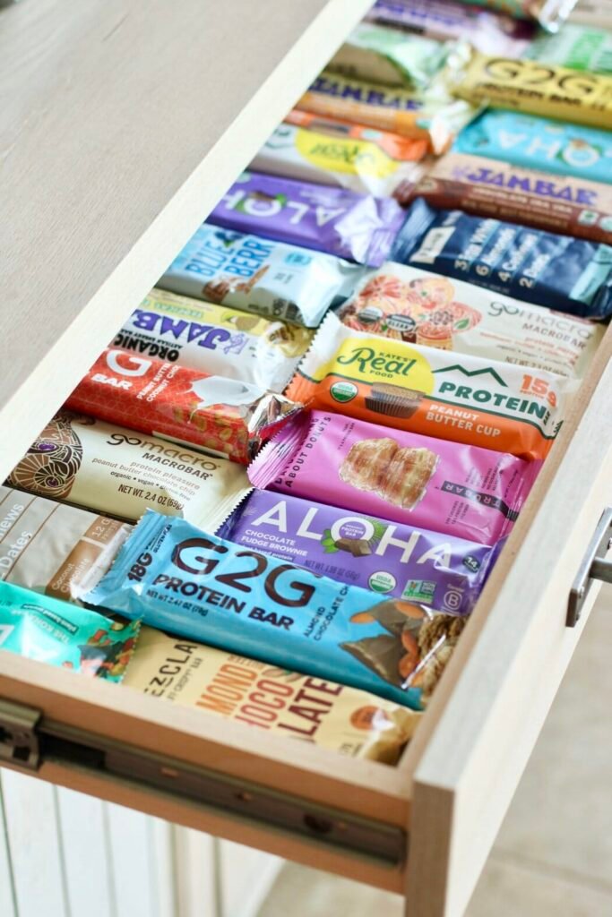 An open slide-out kitchen draw filled with rows of protein bars.